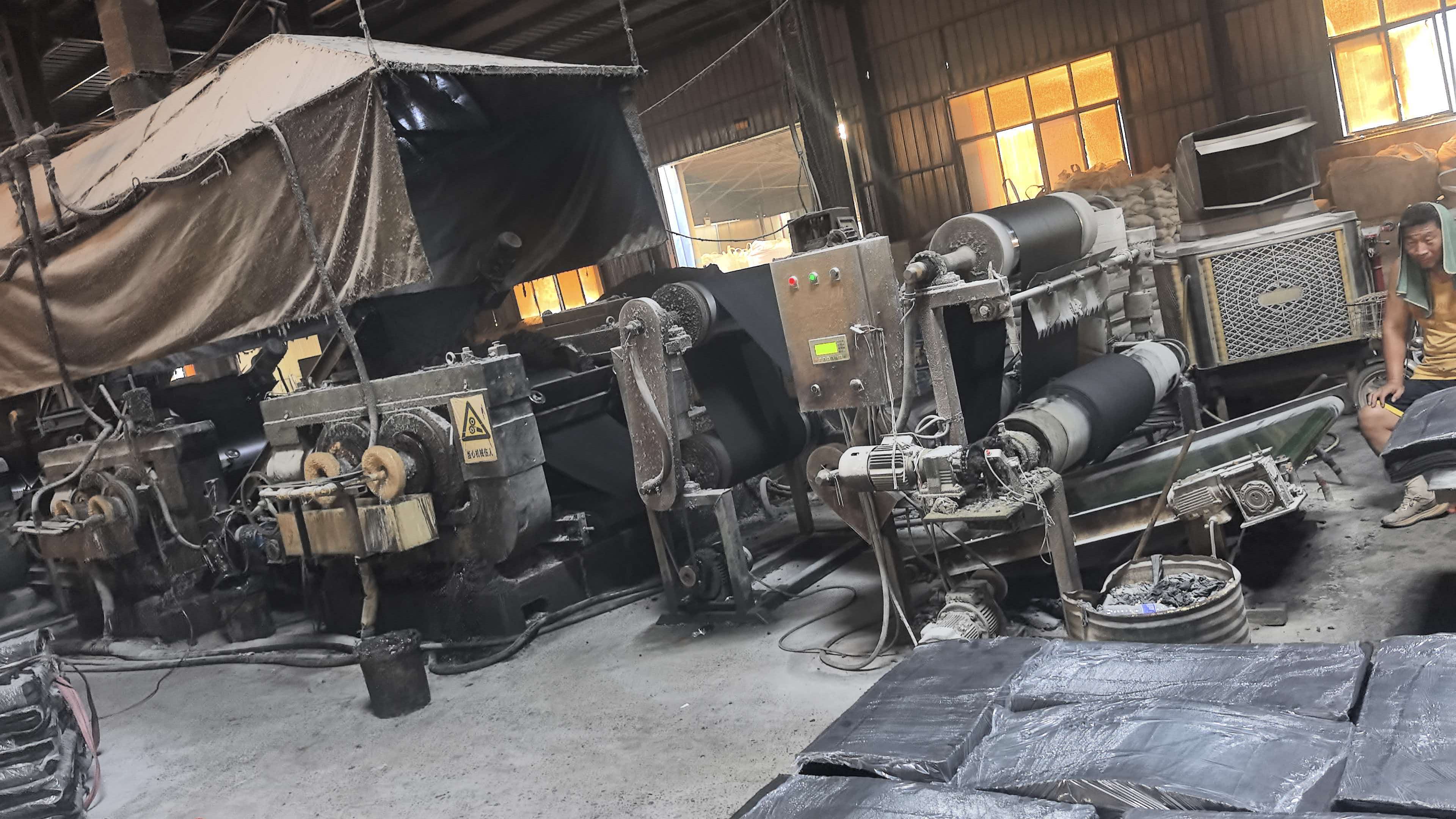 Finished reclaimed rubber sheets staged near the warehouse for weighing and storage
